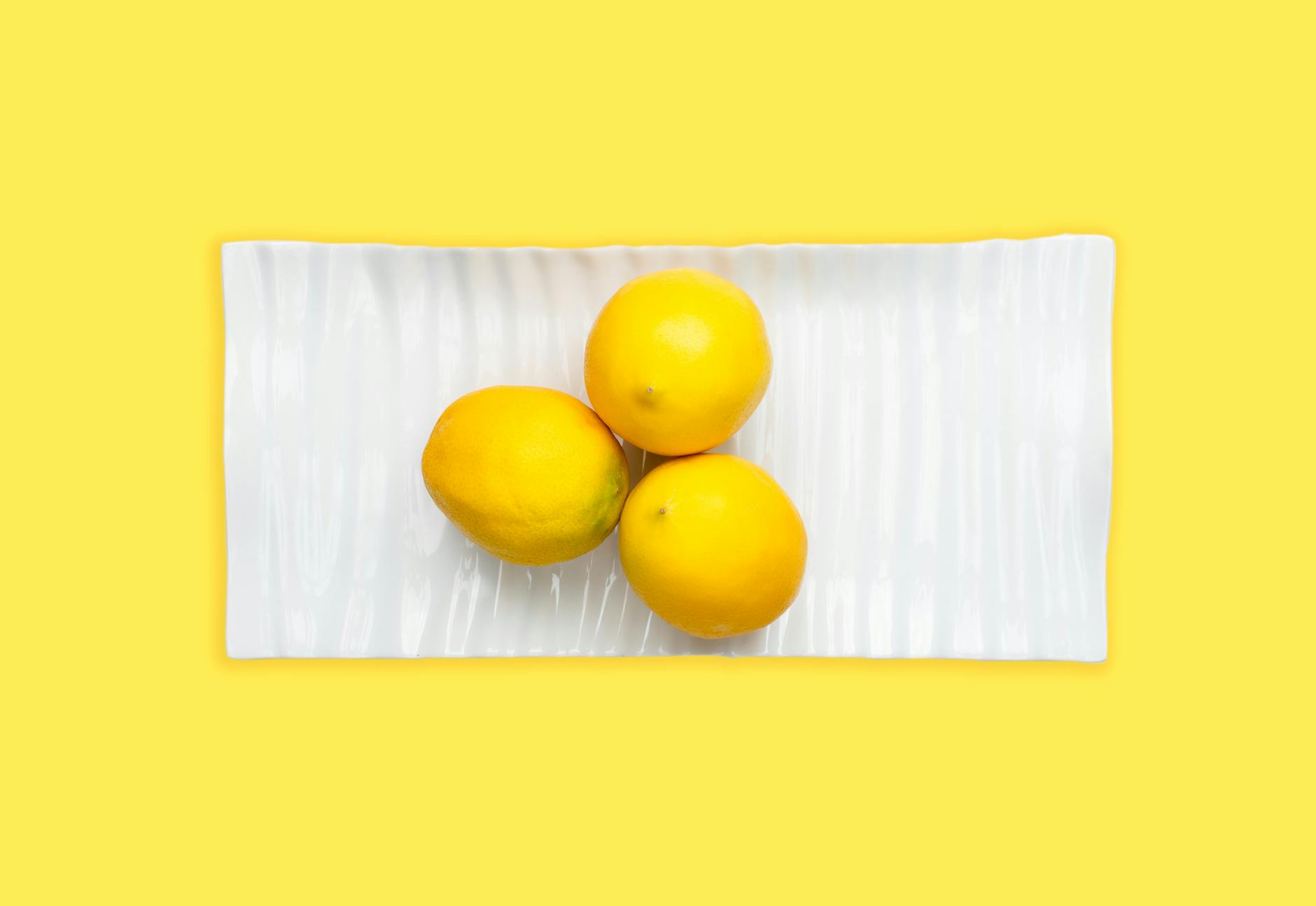 Blue clitoral vibrator surrounded by flowers and citrus slices on a bright yellow background