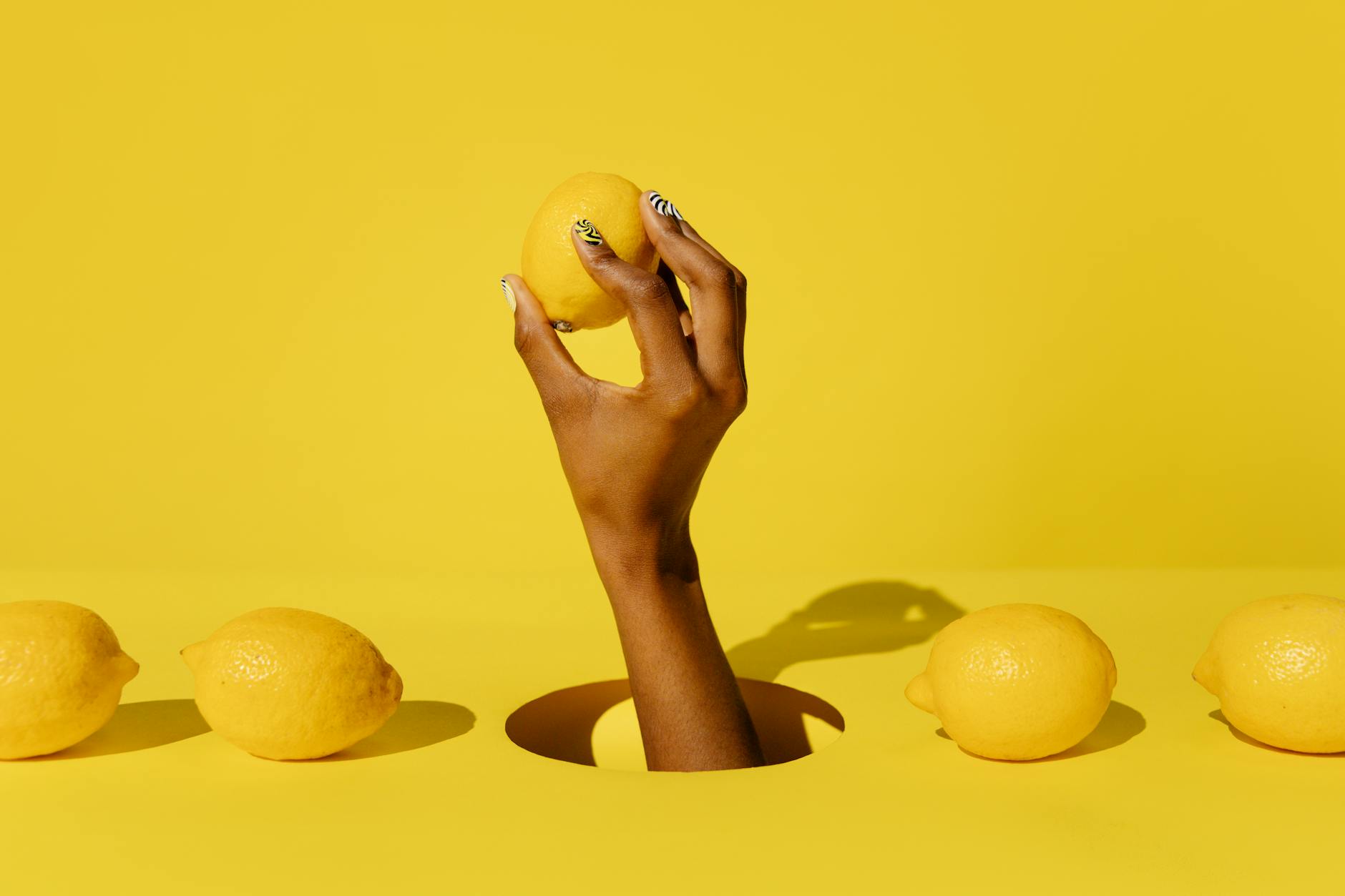 A hand holding a bright lemon against a vivid yellow background, symbolizing fresh sensation and renewal