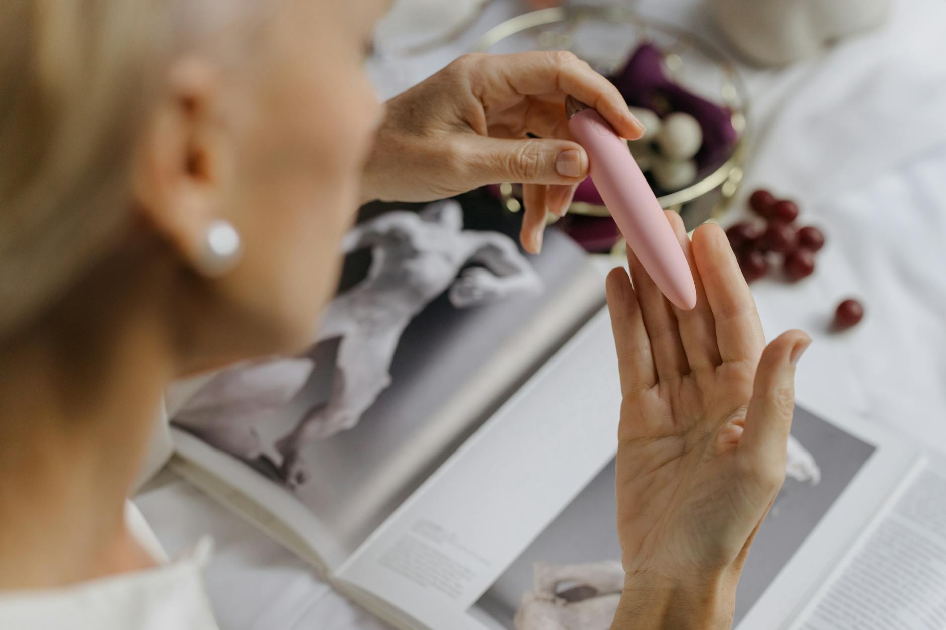 Woman thoughtfully holding two colorful silicone vibrators, exploring pleasure tools with intention and calm