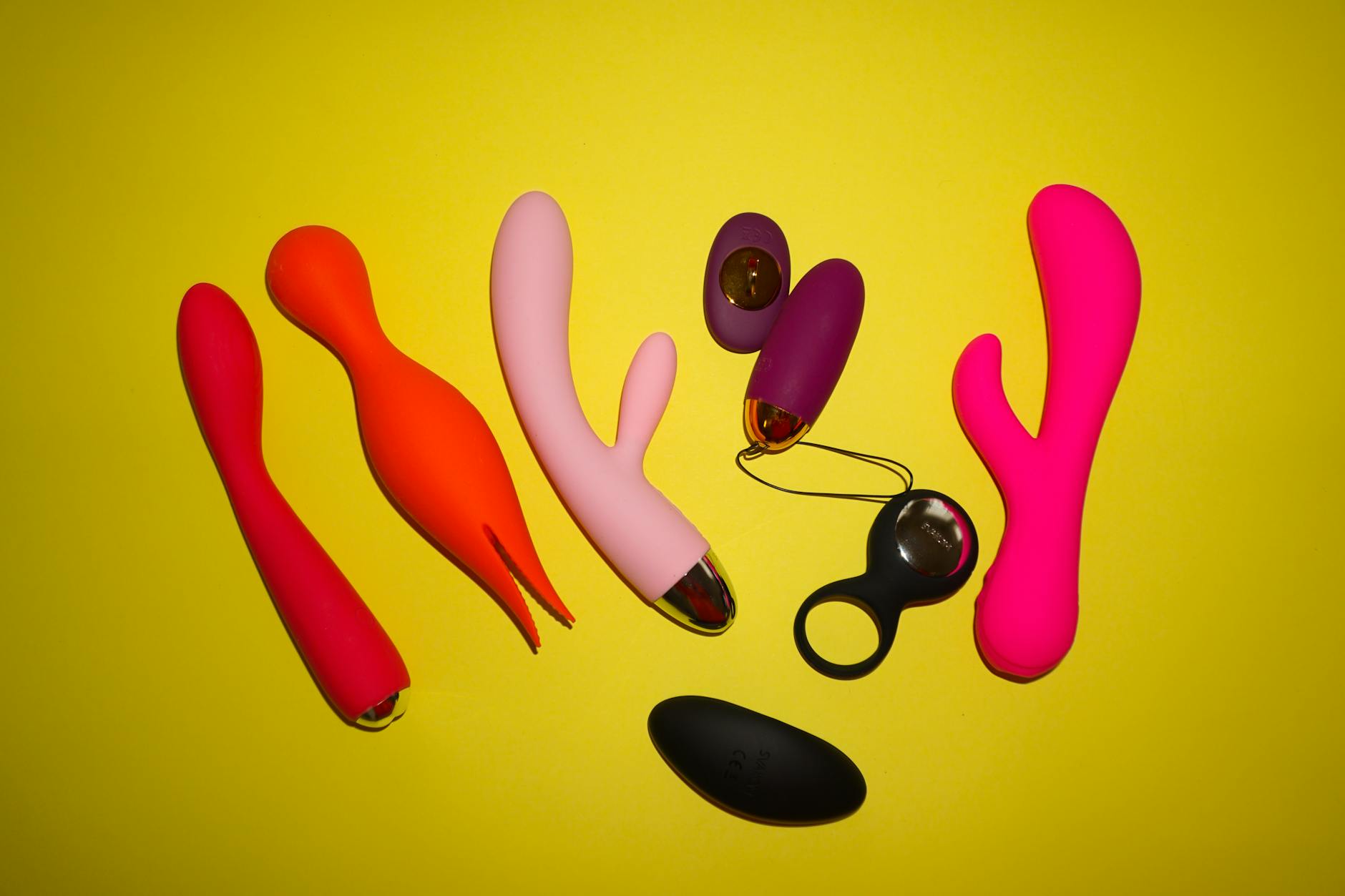 Close-up of hands holding a sleek vibrator against a purple background, showing intimate touch